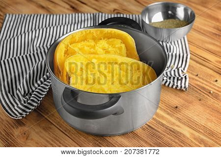 Stewpot with cut spaghetti squash on wooden background