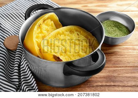 Stewpot with cut spaghetti squash on wooden background