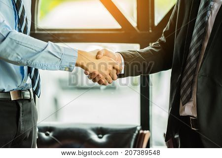 Two confident business man shaking hands during a meeting in the workplace. Business partnership agreement concept.