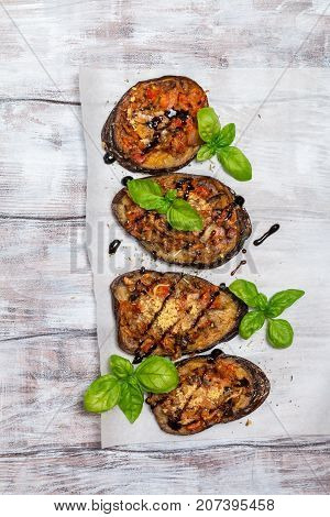 Baked eggplant stuffed with vegetables and cheese with addition aromatic herbs and sauce on paper. Delicious vegetarian dish. top view, sopy space