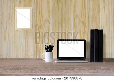 Laptop computer on Workspace and office supplies office wood table and blank photo frame on wood wall at home or studio. Mock up.