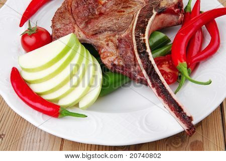 cibo di carne: manzo alla griglia di ricambio rib su piatto bianco con pepe timo e pomodoro sul tavolo di legno