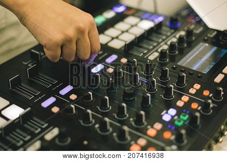 Close-up hands of soundman working with audio mixing board.