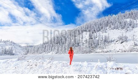 A young girl admires the winter landscape on the lake. Beautiful lake Amut in taiga hills on Far East of Russia in early october. Mountain lake in winter. Beautiful nature. Snowy weather.