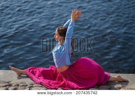 Yoga outdoors. Sporty fit caucasian woman in red skirt doing hanumanasana pose posture in nature