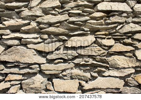 A wall made of different stones of light color.
