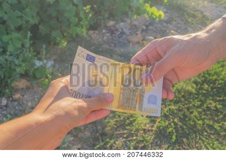 Man's hand with banknote of euro gives it to the woman's hand
