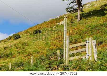 Rural sign post and wooden stile on a hiking trail leading up a mountain trail on in Wales UK with generous copy space