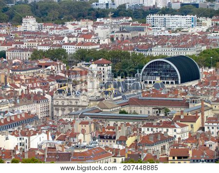 Aerial view of a cityscpae of downtown Lyon in France with plenty of red roofs and white old buildings including the opera and the city hall