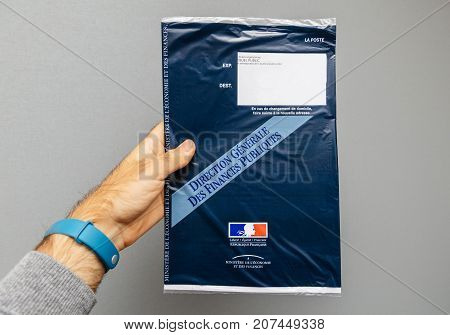 PARIS FRANCE - OCT 4 2017: Man holding against gray background envelope containing Taxe d'habitation (rates property tax) which is sent once per year to very household owner or people who rent a house apartment