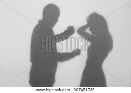 Silhouette of man hurting his wife on white background. Domestic violence concept