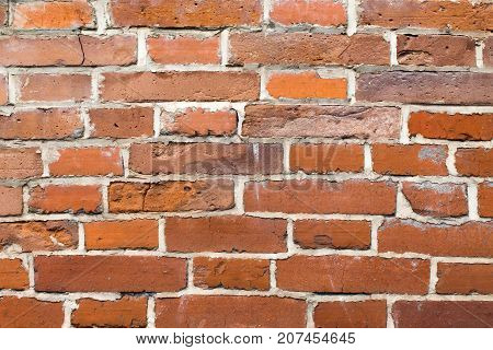 An old brick masonry wall of a warehouse made of red brick.