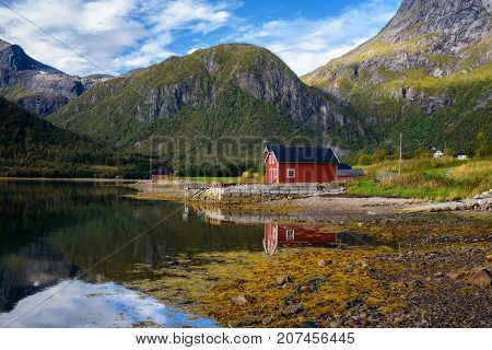 Traditional red rorbu cottages at the sea under the mountains on Lofoten islands in Norway.