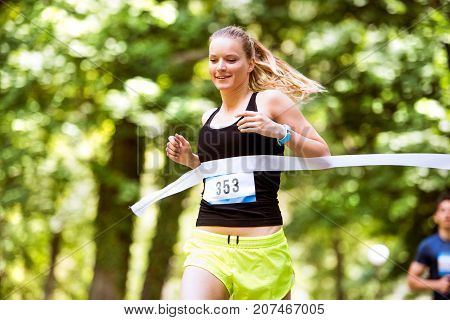 Beautiful young woman running the race crossing the finish line.