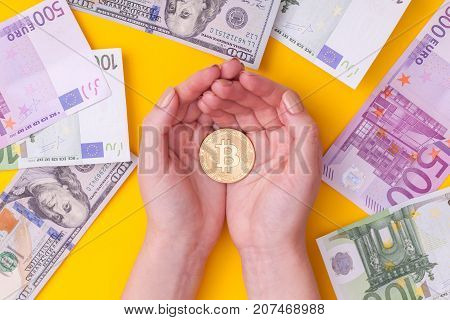 the girl is holding bitcoin in her hands against the background of dollars and euros. concept of currency exchange