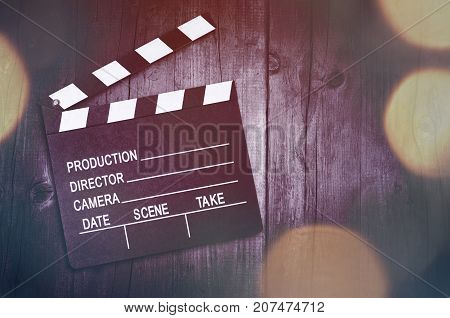 Movie clapper board on wooden background with bokeh lights