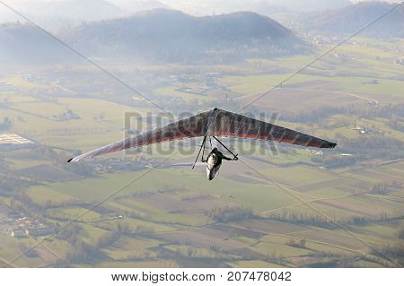extreme sport with a man flying with his hang glider above the plain