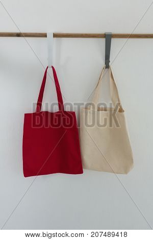 Bags hanging on hook against white wall