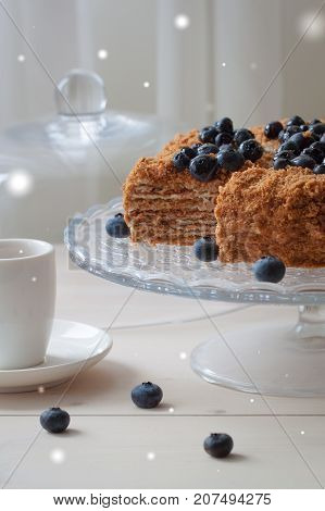 Homemade honey cake with blueberries on the light wooden background