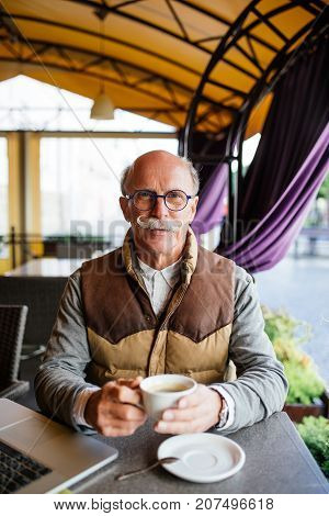 Elderly Man Having An Espresso On A Terrace Of Cafe