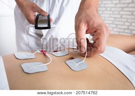 Close-up Of A Therapist's Hand Placing Electrodes On Woman's Stomach
