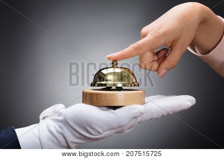 Customer Ringing Service Bell Held By Customer In Front Of Grey Background