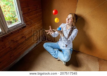 beautiful young smiling woman sitting and juggling