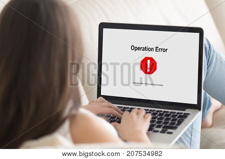 Woman lying on sofa looking at laptop screen, Operation Error message pop up. Computer crashed, software failure during web browsing, watching movie, video call or chatting via social media. Close up.
