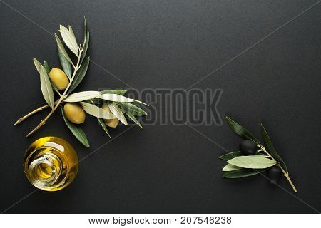 Olive oil and olive branch on black background