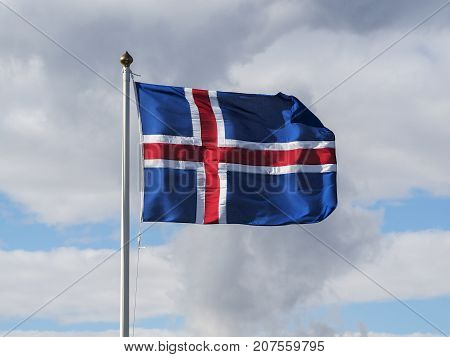 Flag of Iceland against the background cloudy blue sky