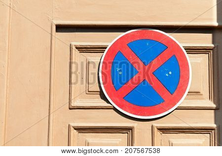 No parking sign on the wooden door to protect entrance from the car drivers. Forbiden parking.