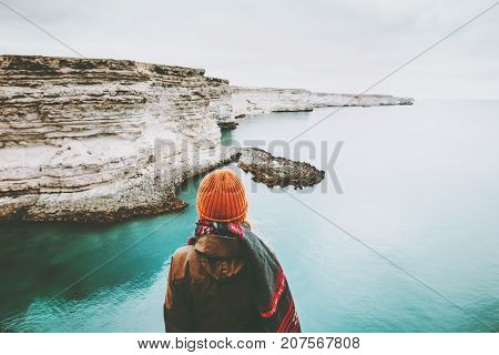 Woman looking at cold sea view alone Travel Lifestyle concept adventure vacations outdoor. Girl wearing fashion orange knitted hat and scarf. Melancholy solitude emotions