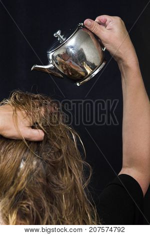 Vertical studio shot of a woman pouring water from a kettle on herr head