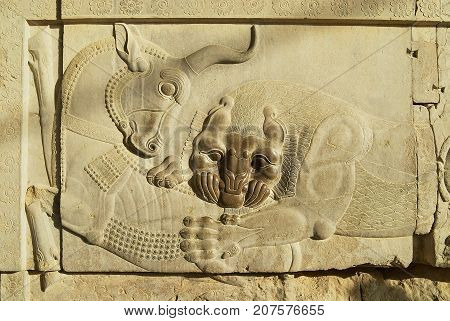 Bas relief of a bull and a lion at the ruins of Persepolis in Shiraz, Iran. This Bas-relief is the symbol in Zoroastrian for Nowruz and eternally fighting Moon and Sun. Persepolis is a UNESCO World Heritage site.