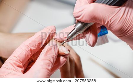 Hardware manicure. Removal of old gel varnish in the salon. Manicure master doing beauty procedure for client, closeup and top view