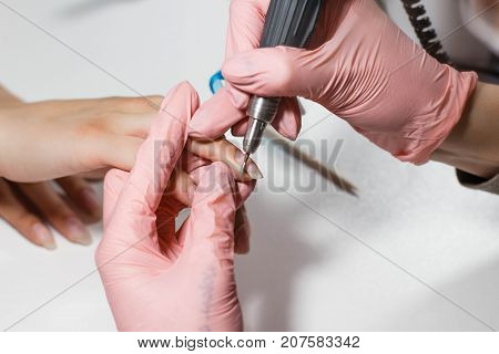 Hardware manicure. Removal of old gel varnish in the salon. Manicure master doing beauty procedure for client, closeup and top view