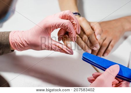 Woman getting nail manicure in salon. Care for hands. manicure master makes the nails smooth using the nail file with smooth ends purple