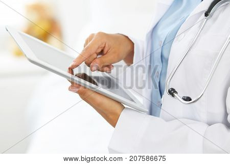Woman doctor using tablet computer while standing straight in hospital.
