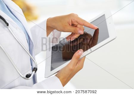 Woman doctor using tablet computer while standing straight in hospital.