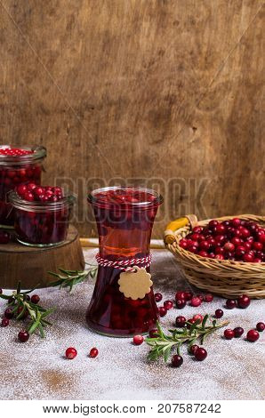 Cranberries with the syrup in glass on wooden background. Selective focus.