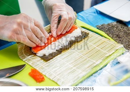 Preparation of a sushi roll in restaurant close up on chef hands