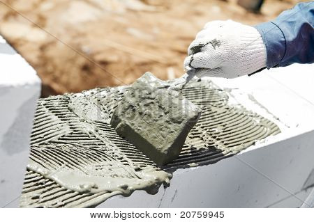 processo de construção de alvenaria de argamassa de cimento adicionando com faca espátula putty