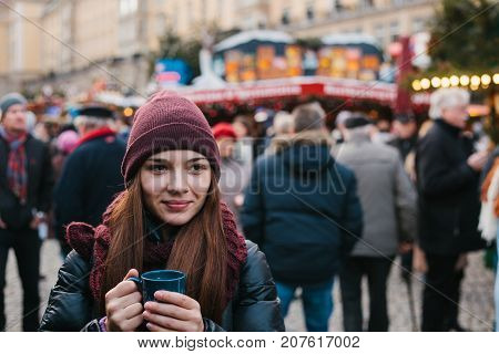Beautiful young girl with a mug of hot drink at the Christmas market in Dresden. Celebrating Christmas in Europe. Holidays.