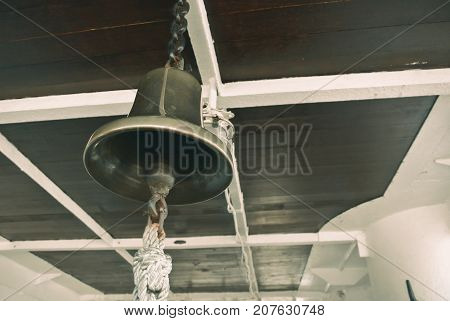 Closeup view of vintage navy ship bell made of brass and the ceiling.