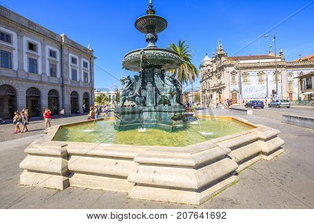 Porto, Portugal - August 11, 2017: Fountain of Lions, 19th century fountain, in Parade Leitao Square and Carmo church famous for azulejos on background. Historical city of Oporto.
