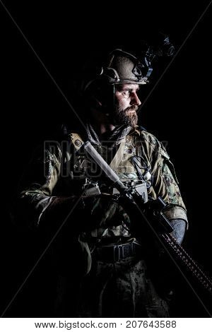 Studio contour backlight shot of special forces soldier in uniforms with weapons, portrait on black background