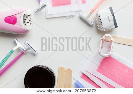 beauty, depilation and hair removal concept - wax with spatula, epilator and safety razor on white background