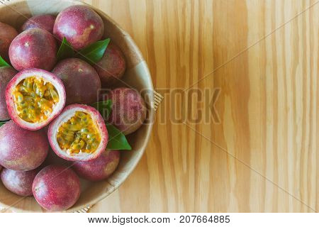 Fresh passion fruit in wood bowl on wood table in top view flat lay with copy space for background or wallpaper. Ripe passion fruit so delicious sweet and sour. Passion fruit is tropical fruit. Passion fruit background concept.