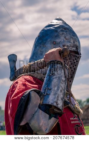 Knight in armor and iron helmet with an ax and shield