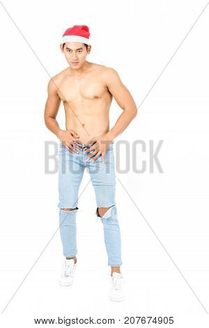 Christmas concept : Handsome muscular young Asian man shirtless in fashionable blue jean wearing red Santa Hat isolated on white background